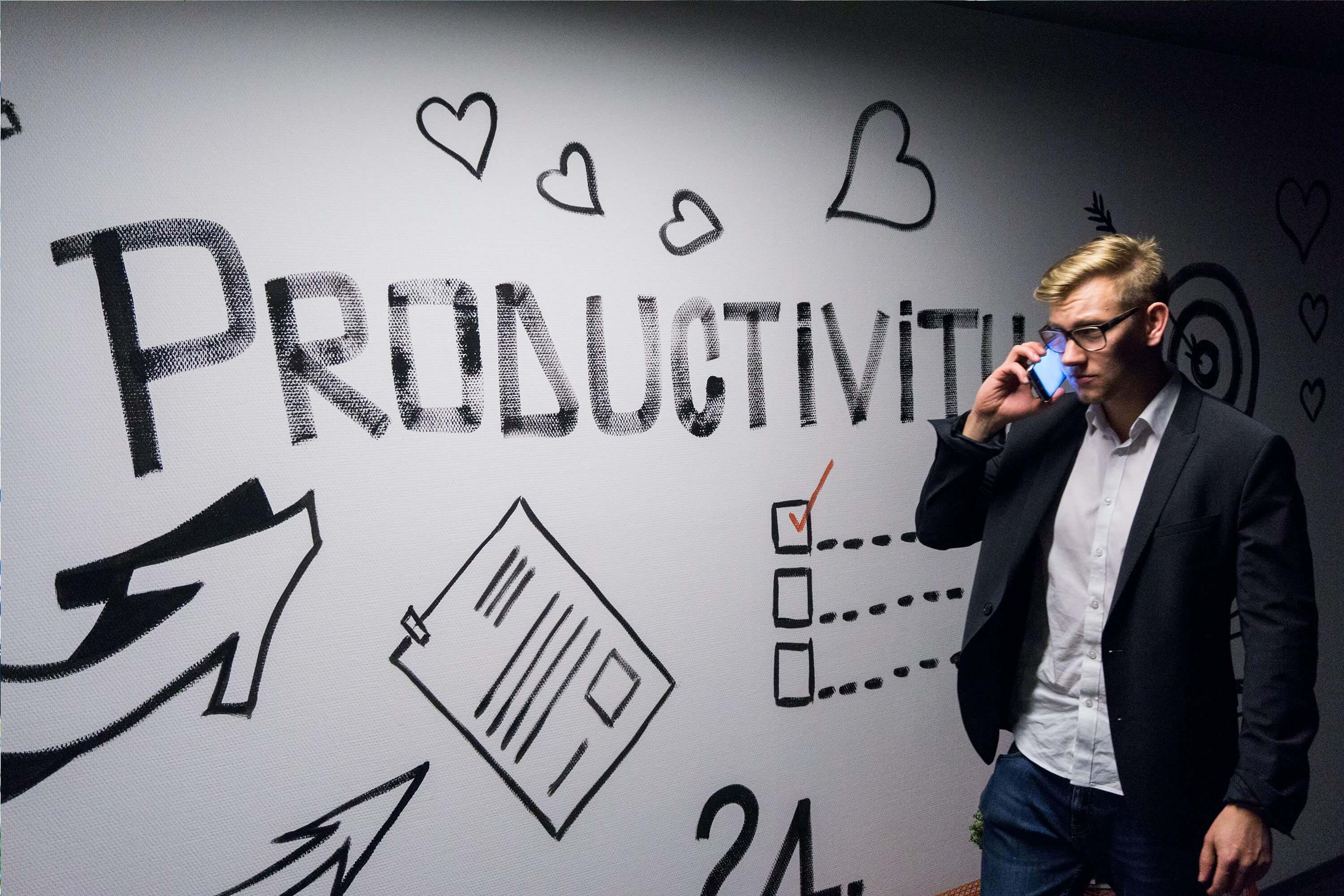 man standing in front of a mural that reads "productivity"