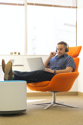 man-sitting-in-chair-wearing-headphones-using-laptop