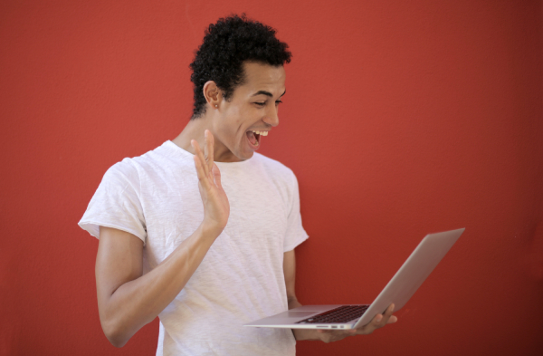 happy person in white t-shirt waving at a laptop